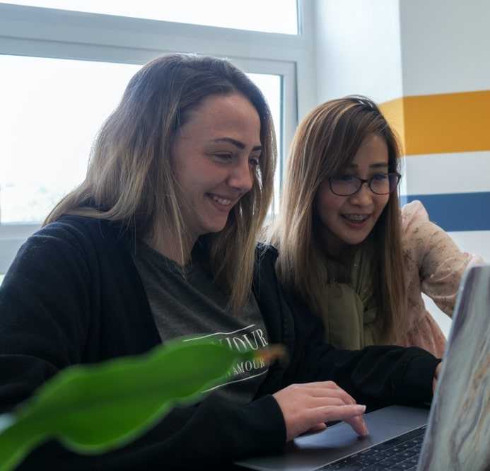 Girls smiling while seeing their laptop screens